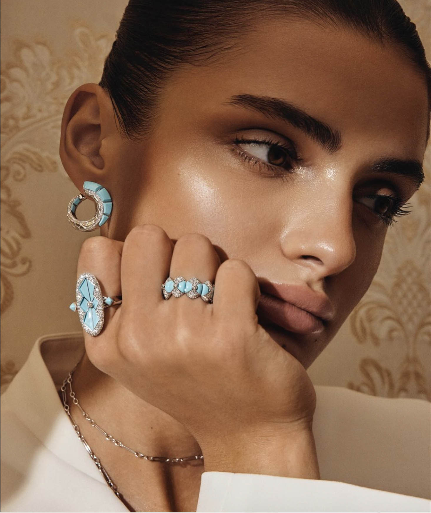 Close-up of a woman wearing turquoise and diamond jewelry, including earrings, rings, and a necklace